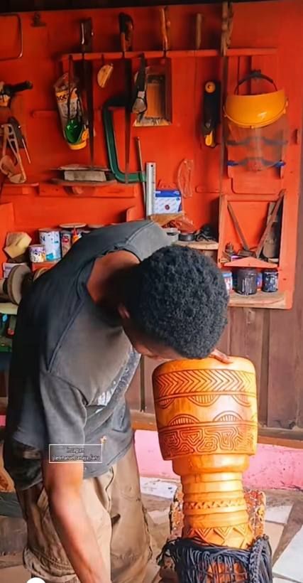Emmanuel finishing a carved djembe shell